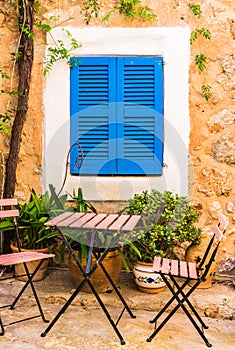 Cosy terrace place with chairs and table and blue window shutter of mediterranean house