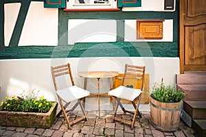 Cosy wooden table and chairs set in front of a typica german old style house