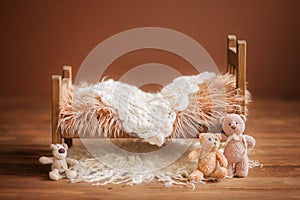 Cot for a newborn on a brown background with toys and a white rug, background