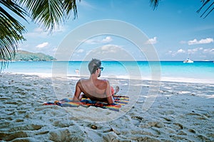 Cote D`Or Beach, Praslin Seychelles tropical Island, young men in swim short on the white beach with huge boulders and