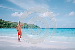 Cote D`Or Beach, Praslin Seychelles tropical Island, young men in swim short on the white beach with huge boulders and