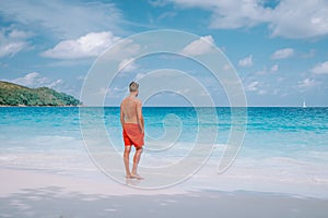 Cote D`Or Beach, Praslin Seychelles tropical Island, young men in swim short on the white beach with huge boulders and