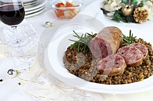 Cotechino with lentils served on a plate and a glass of red wine. Christmas holiday.