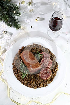 Cotechino with lentils served on a plate and a glass of red wine. Christmas holiday.