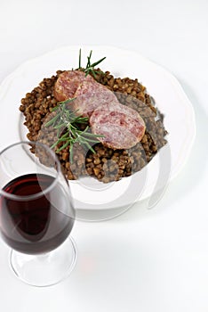 Cotechino with lentils served on a plate and a glass of red wine. Christmas holiday.