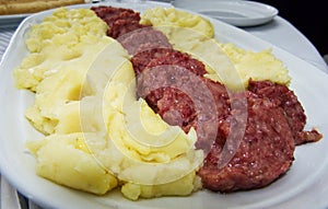 Cotechino, pork sausage, with mashed potato in a white plate, italian food