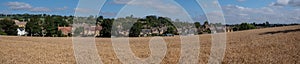 The Cotswold town of Chipping Campden, Gloucestershire, UK on the horizon. Field of wheat in foreground.