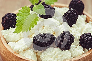 Cottage cheese with blackberry in a wooden bowl/cottage cheese with blackberry in a wooden bowl. Close up