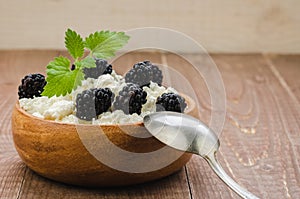 Cottage cheese with blackberry in a wooden bowl./cottage cheese with blackberry in a wooden bowl on a wooden background