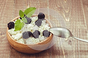 Cottage cheese with blackberry in a wooden plate/cottage cheese with blackberry in a wooden plate. selective focus. Toned