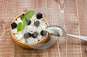 cottage cheese with blackberry in a wooden plate/cottage cheese with blackberry in a wooden plate. Top view