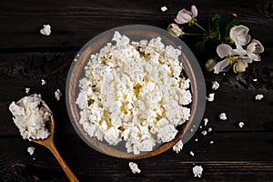 Cottage cheese in a bowl on wooden table. Style rustic.