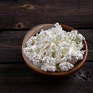 Cottage cheese in a bowl on wooden table. Style rustic.