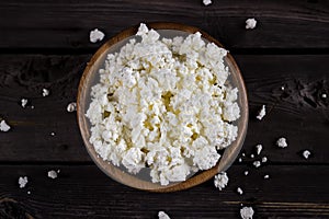 Cottage cheese in a bowl on wooden table. Style rustic.