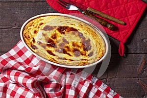 Cottage cheese casserole in an oval ceramic form on a wooden background. Rustic style.