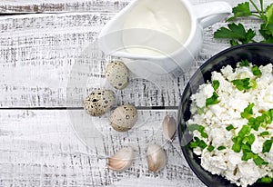 Cottage cheese with chives in black ceramic bowl on rustic woode