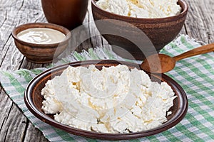 Cottage cheese on dish with spoon and cream in bowl