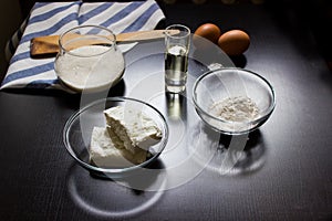 Cottage cheese, flour, eggs, oil, salt on a dark background