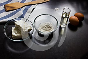 Cottage cheese, flour, eggs, oil, salt on a dark background