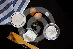 Cottage cheese, flour, eggs, oil, salt on a dark background