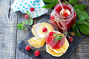 Cottage cheese fritters, pancakes with raspberry jam and fresh raspberries on a wooden rustic table. Copy space for your text