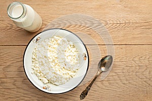Cottage cheese with milk in a bowl on a wooden table