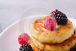 Cottage cheese pancakes, curd fritters dessert with raspberry and blackberry berries in plate