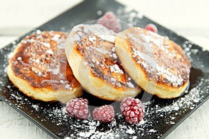 Cottage cheese pancakes on dark plate over white rustic wooden t