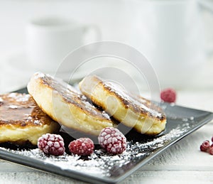 Cottage cheese pancakes on dark plate over white rustic wooden t