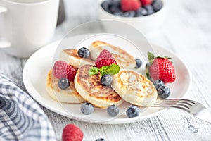 Cottage cheese pancakes with fresh berries on white wooden table. Breakfast or lunch. Syrniki
