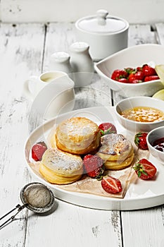 Cottage Cheese Pancakes with fresh strawberries and jam. Curd Cheese Pancakes on a white plate sprinkled with powdered sugar