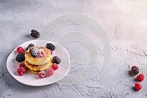 Cottage cheese pancakes and powdered sugar, curd fritters dessert with raspberry and blackberry berries