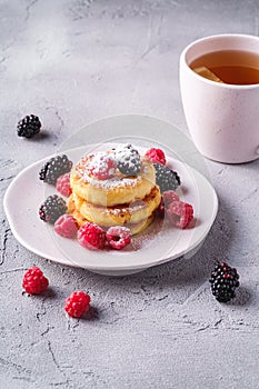 Cottage cheese pancakes and powdered sugar, curd fritters dessert with raspberry and blackberry berries in plate