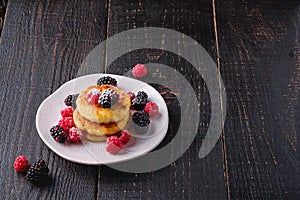 Cottage cheese pancakes and powdered sugar, curd fritters dessert with raspberry and blackberry berries in plate