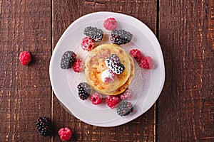 Cottage cheese pancakes and powdered sugar, curd fritters dessert with raspberry and blackberry berries in plate