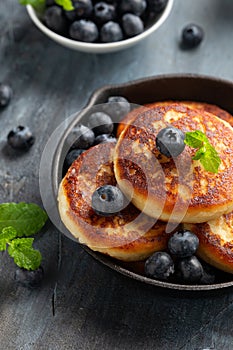 Cottage cheese pancakes served in cast iron frying pan with blueberries and mint leaves. Healthy breakfast food.