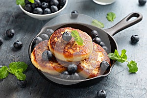 Cottage cheese pancakes served in cast iron frying pan with blueberries and mint leaves. Healthy breakfast food.