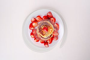 Cottage cheese pancakes with sliced strawberries on white plate