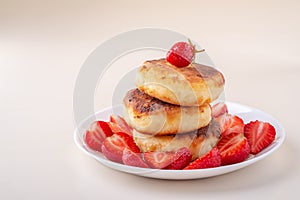 Cottage cheese pancakes with sliced strawberries on white plate isolated