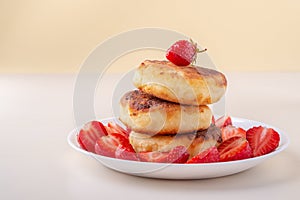 Cottage cheese pancakes with sliced strawberries on white plate isolated