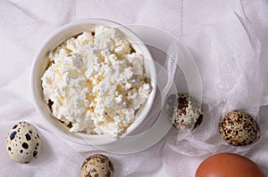 Cottage cheese and quail eggs on a light background top view