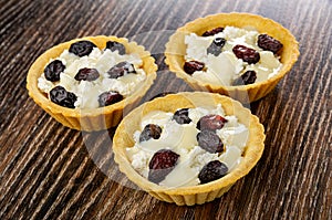 Cottage cheese with raisin and condensed milk in tartlets on wooden table