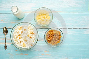 Cottage cheese with raisins and pineapple zucchini, with milk in a bowl on a blue wooden table. Diet, tasty and healthy food.