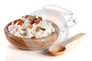 Cottage cheese with raisins and sour cream in a wooden bowl isolated on a white background