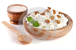 Cottage cheese with raisins in a wooden bowl isolated on a white background