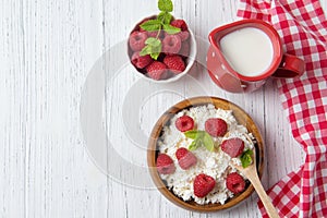 Cottage cheese with raspberries and green mint leaves, fresh berries and milk jug, healthy breakfast concept, top view