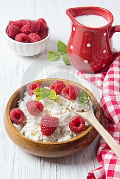 Cottage cheese with raspberries and mint leaves, fresh berries and milk jug, healthy breakfast concept