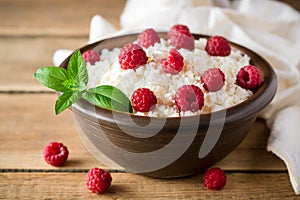 Cottage cheese with raspberry and mint in ceramic bowl on rustic wooden table