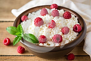 Cottage cheese with raspberry and mint in ceramic bowl on rustic wooden table