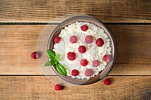 Cottage cheese with raspberry and mint in ceramic bowl on rustic wooden table